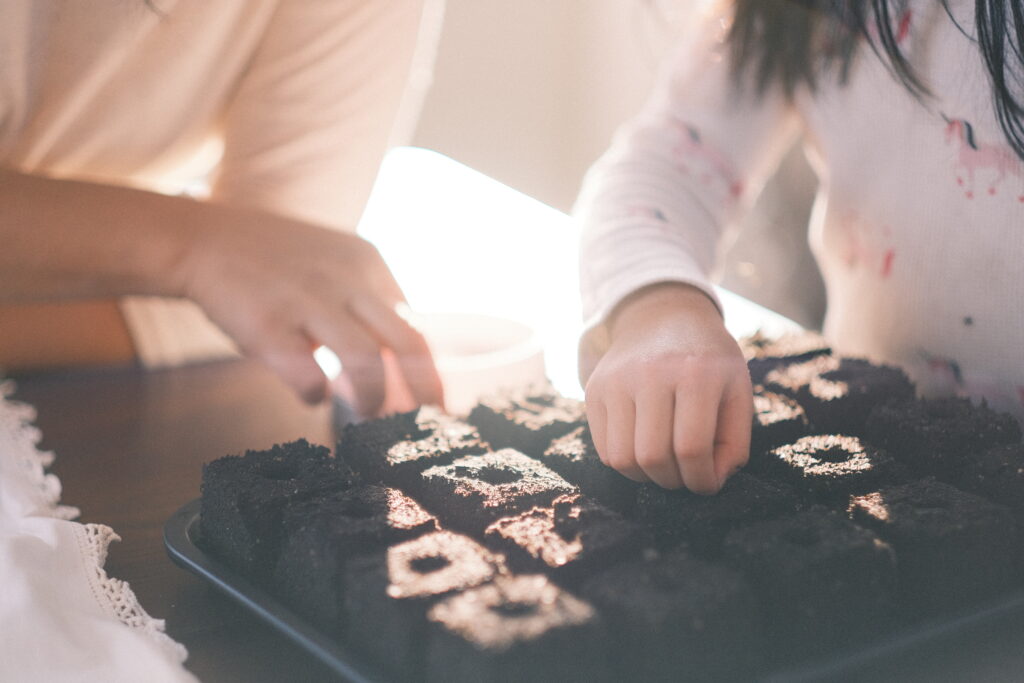 mom and daughter sowing seed into soil block